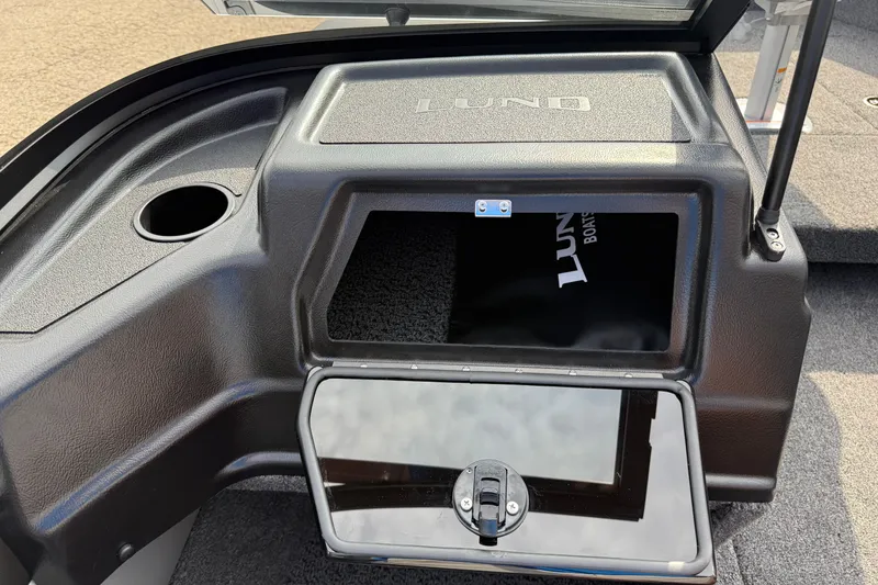 Slide: The Image of 2026 Lund 1875 Crossover XS boat storage compartment with open lid and cup holder. - 26