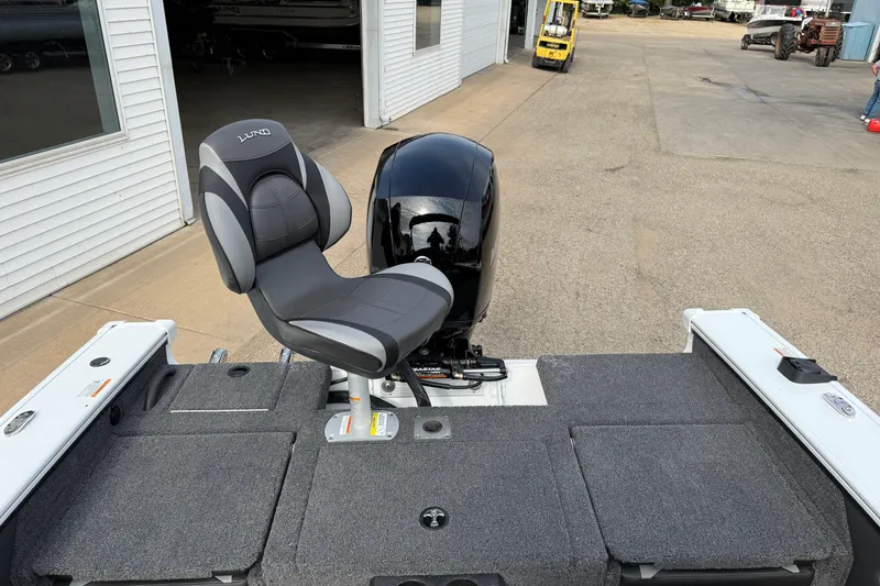 Slide: The Image of 2026 Lund 1875 Crossover XS boat with cushioned seat and motor, parked outside. - 31