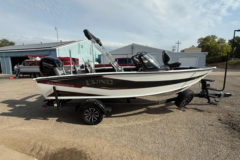 Slide: The Image of 2026 Lund 1875 Crossover XS boat on trailer, parked outside a building. - 4
