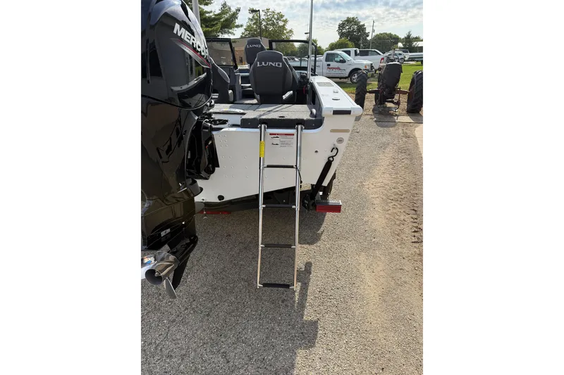 Slide: The Image of 2026 Lund 1875 Crossover XS boat with ladder and Mercury engine, parked outdoors. - 7