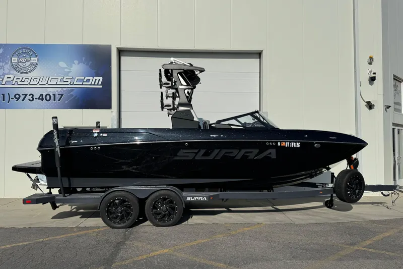 The Image of 2021 Supra SL 575 boat on trailer outside a marine products store. - 0