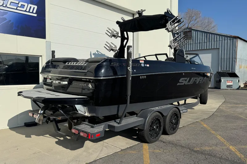 Slide: The Image of 2021 Supra SL 575 boat on trailer, black exterior, parked outside a building. - 1
