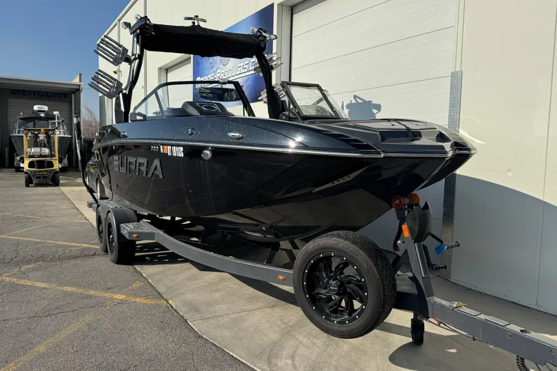 Slide: The Image of 2021 Supra SL 575 boat on trailer, black exterior, parked outside a building. - 3