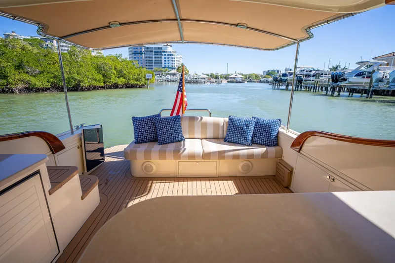 Slide: The Image of 2017 Palm Beach Motor Yachts PB45 interior with striped seating, blue cushions, and scenic water view. - 12