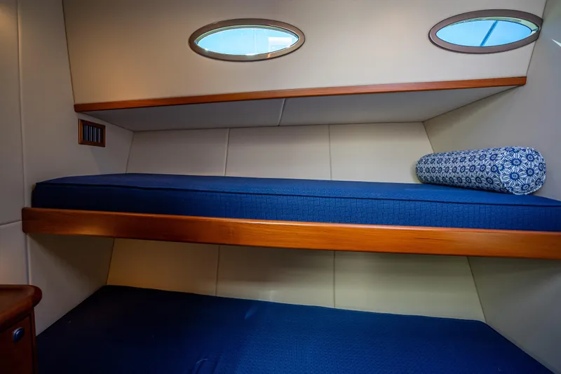 Slide: The Image of 2017 Palm Beach Motor Yachts PB45 cabin with blue bedding and porthole windows. - 47