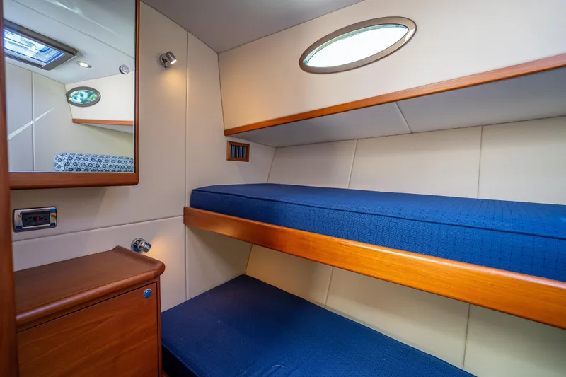 Slide: The Image of 2017 Palm Beach Motor Yachts PB45 cabin with blue bunk beds and wooden accents. - 48