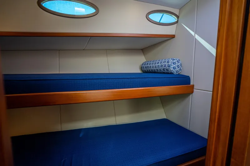 Slide: The Image of 2017 Palm Beach Motor Yachts PB45 cabin with blue bunk beds and porthole windows. - 49