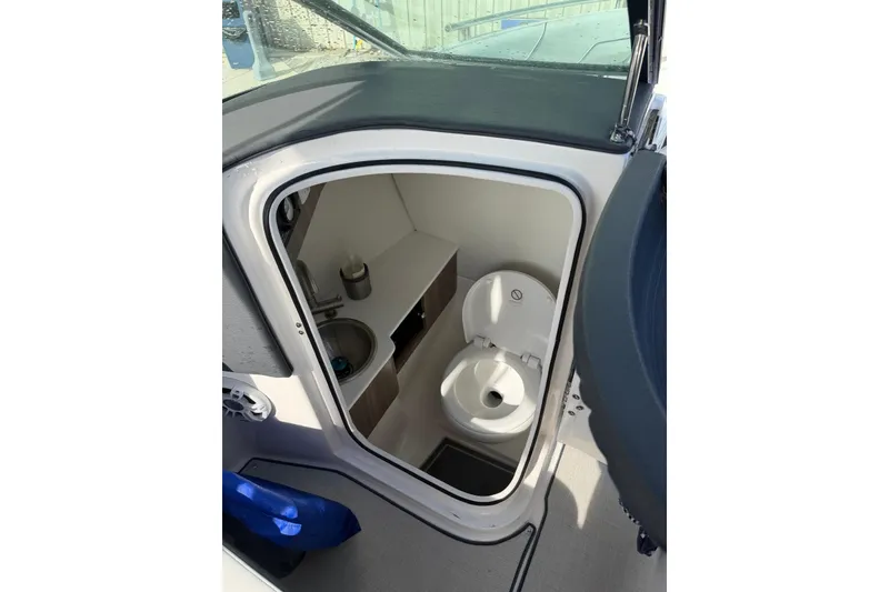 Slide: The Image of 2023 Regal LX4 boat interior with compact bathroom, featuring a toilet and sink. - 10