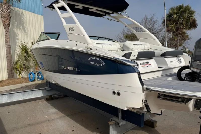 Slide: The Image of 2023 Regal LX4 boat on trailer, white and blue exterior, docked outdoors. - 4
