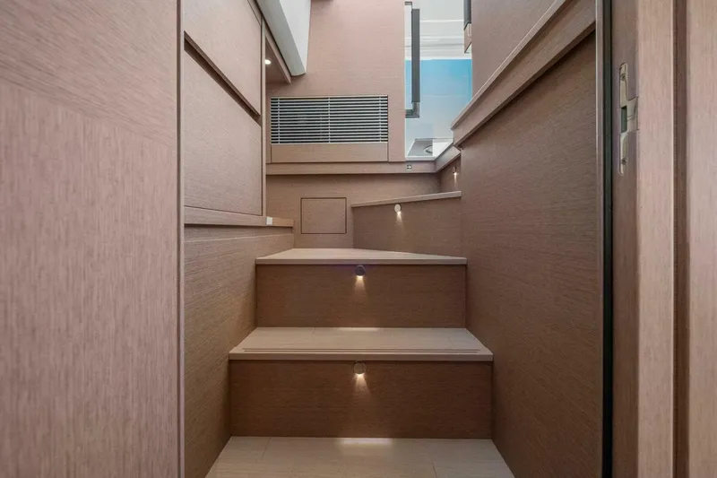 Slide: The Image of Interior stairs of 2022 Prestige 520 yacht, featuring modern wood design and ambient lighting. - 45