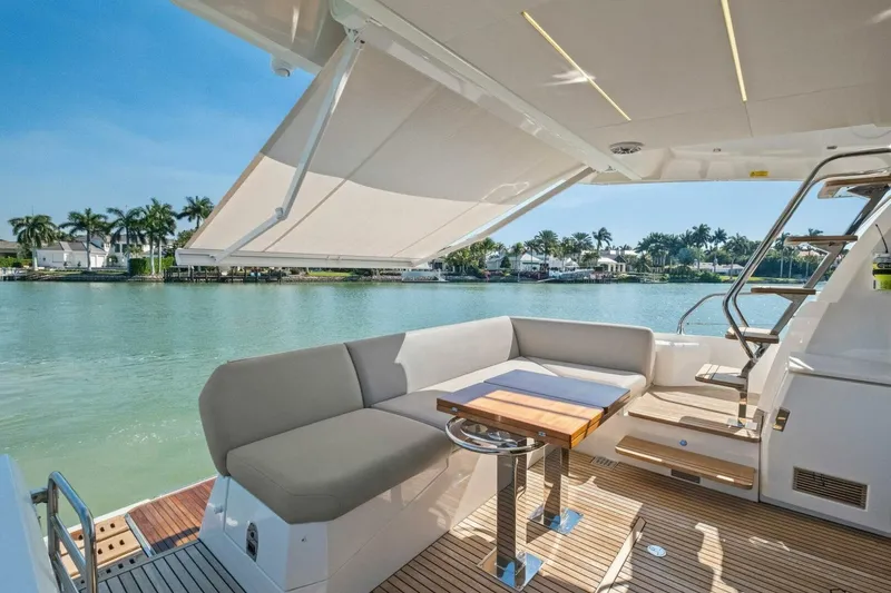 Slide: The Image of Luxurious 2022 Prestige 520 yacht deck with seating, table, and scenic waterfront view. - 5