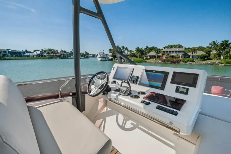 Slide: The Image of Helm of 2022 Prestige 520 yacht with modern navigation equipment, overlooking serene waterfront homes. - 63