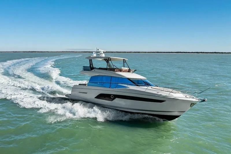 Slide: The Image of 2022 Prestige 520 yacht cruising on open water under clear blue skies. - 82