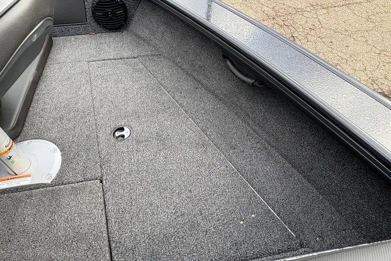 Slide: The Image of Interior of 2026 Lund 1875 Crossover XS boat, featuring carpeted flooring and storage compartment. - 12