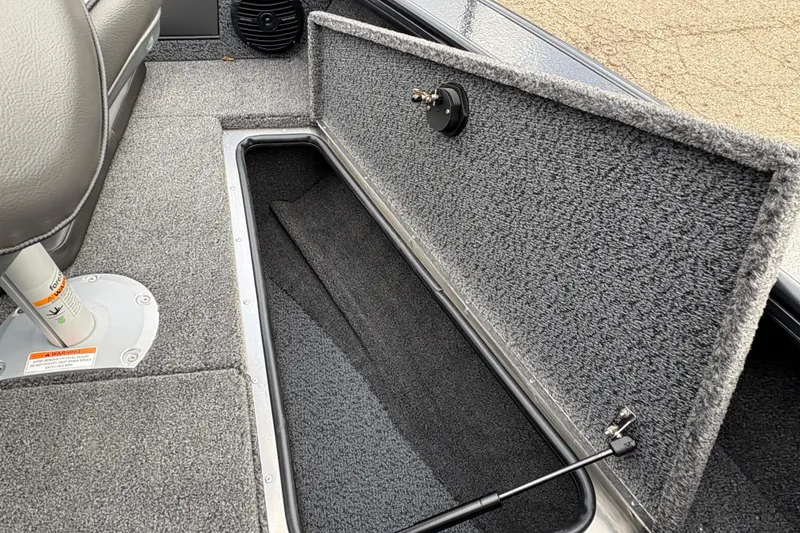 Slide: The Image of 2026 Lund 1875 Crossover XS boat interior storage compartment with gray carpet. - 13