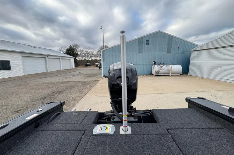 Slide: The Image of 2026 Lund 1875 Crossover XS boat with motor, parked near industrial buildings. - 27