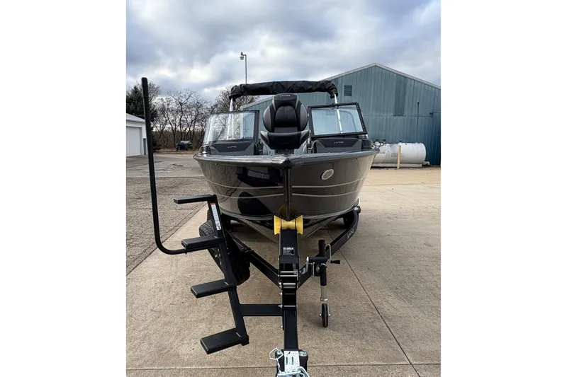 Slide: The Image of 2026 Lund 1875 Crossover XS boat on trailer, parked outdoors under cloudy sky. - 7