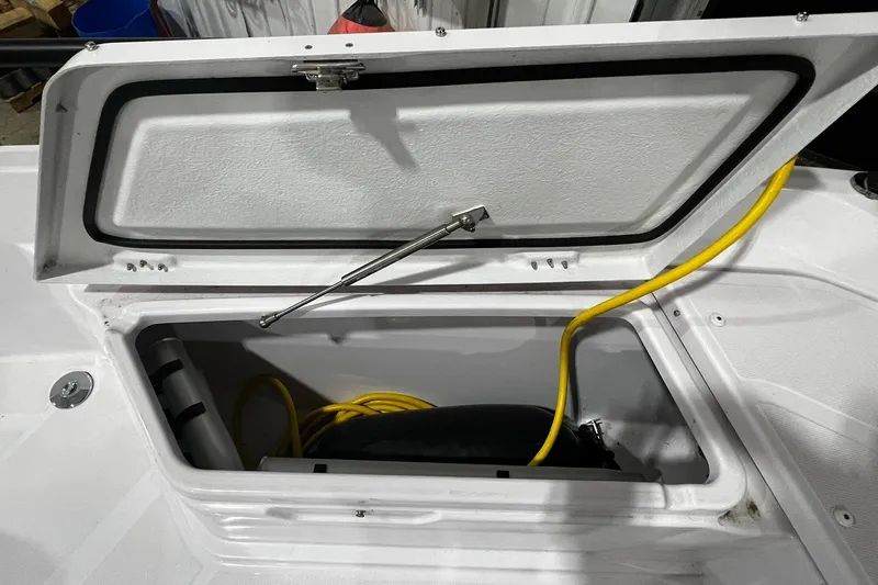 Slide: The Image of Open storage compartment in 2025 Axopar 29 XC Cross Cabin boat with yellow cable inside. - 4
