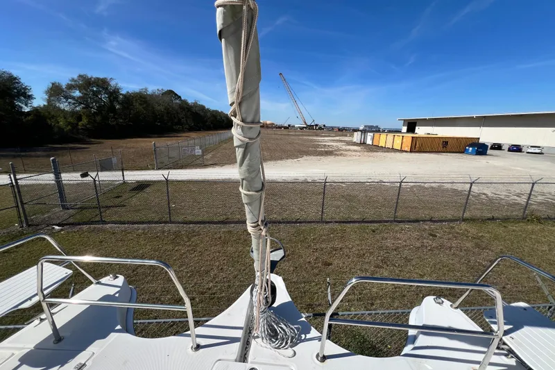 Slide: The Image of Sailboat Gemini Legacy 35, 2013 model, docked near industrial area with clear blue sky. - 103