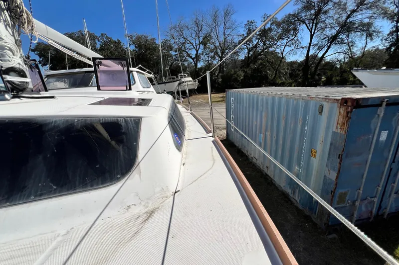 Slide: The Image of Catamaran Gemini Legacy 35, 2013 model, docked near shipping container and trees. - 125