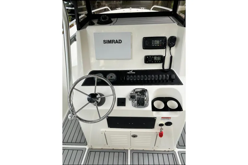 Slide: The Image of 2005 Mako 232 Center Console boat dashboard with Simrad electronics and steering wheel. - 5