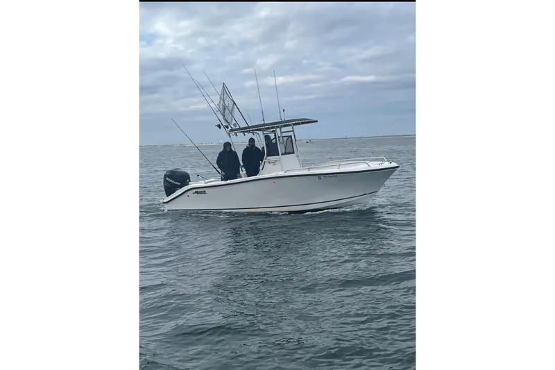 Slide: The Image of 2005 Mako 232 Center Console boat on water with fishing rods and two people onboard. - 8