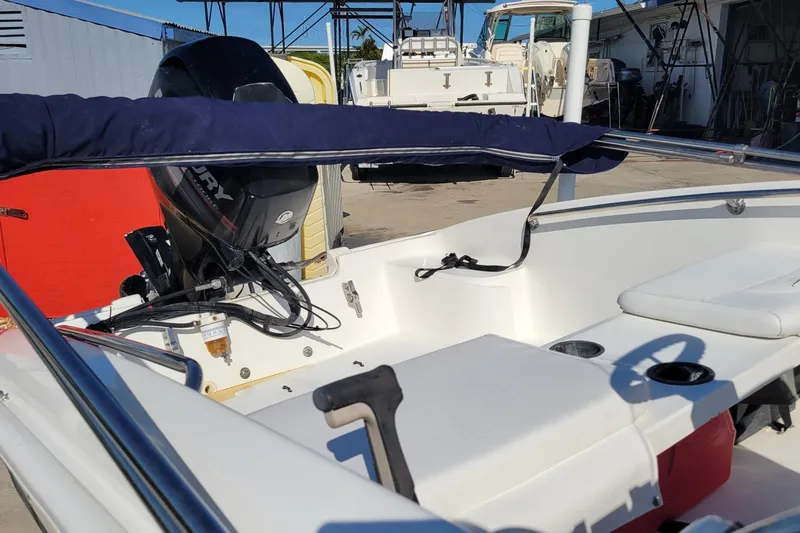 Slide: The Image of 2015 Boston Whaler 150 Super Sport boat interior with Mercury engine, docked outdoors. - 6