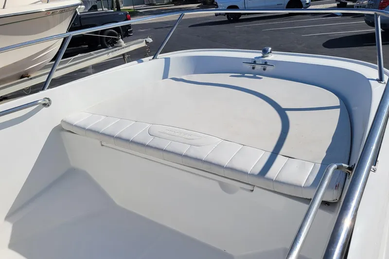 Slide: The Image of 2015 Boston Whaler 150 Super Sport boat interior with cushioned seating and railing. - 9