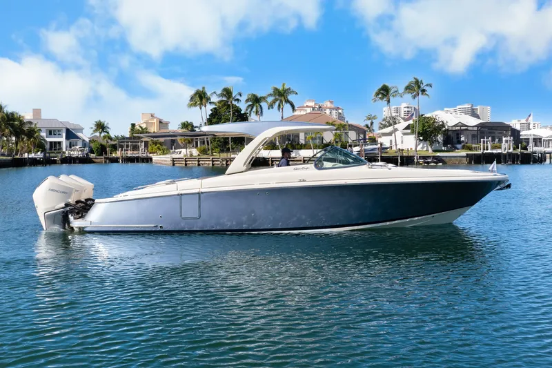 Slide: The Image of 2021 Chris-Craft Launch 35 GT OB boat on calm water, with palm trees and buildings in the background. - 11