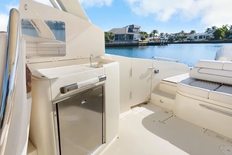 Slide: The Image of 2021 Chris-Craft Launch 35 GT OB boat interior with sink and seating, overlooking waterfront homes. - 21