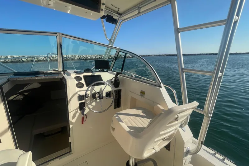Slide: The Image of 2006 Parker 2310 boat interior with steering wheel, dashboard, and open water view. - 7