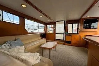 Slide: The Image of 1999 Mikelson 50 Sportfisher interior with beige seating, wooden accents, and large windows. - 12