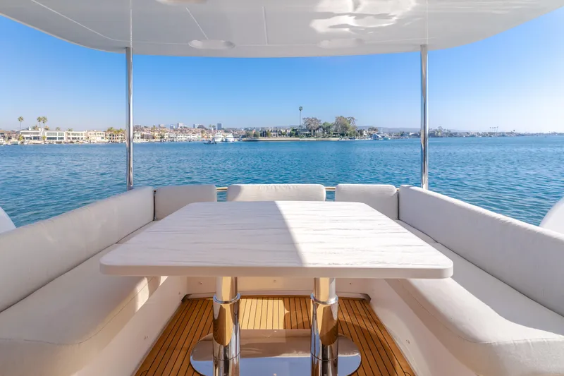 Slide: The Image of Azimut Magellano 66 yacht deck with seating and table, overlooking serene waterfront, 2023 model. - 38