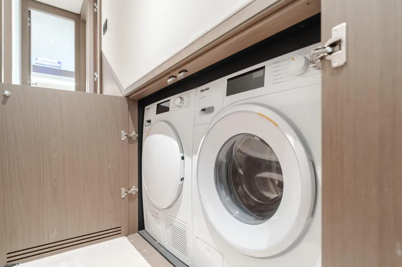 Slide: The Image of Laundry appliances in Azimut Magellano 66 yacht, 2023 model, behind wooden cabinet doors. - 48