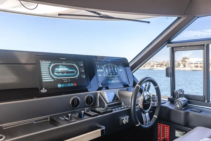 Slide: The Image of 2023 Azimut Magellano 66 yacht cockpit with advanced navigation displays and steering wheel. - 54