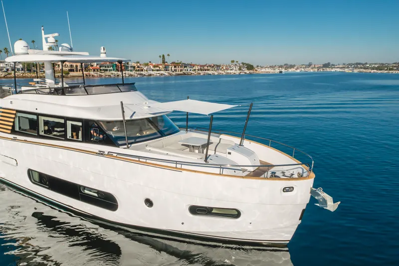 Slide: The Image of 2023 Azimut Magellano 66 yacht cruising on calm waters near a coastal town. - 7