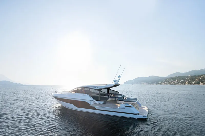 Slide: The Image of 2026 Fairline 58 GTO yacht cruising on serene waters with scenic coastal backdrop. - 2