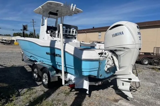 Slide: The Image of 2026 NauticStar 251 Hybrid boat with Yamaha engine on trailer, parked outdoors. - 2