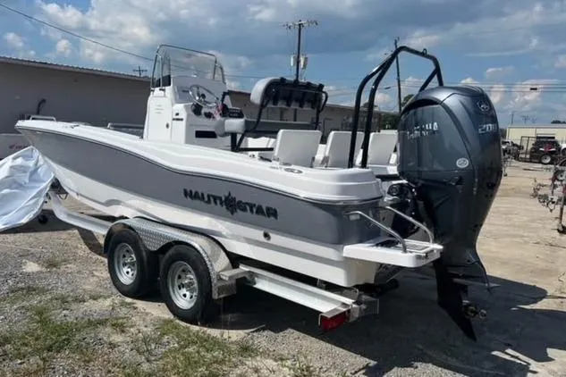 Slide: The Image of 2026 NauticStar 211 Hybrid boat on trailer, parked outdoors under a cloudy sky. - 1