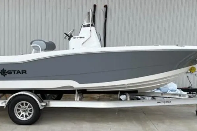 The Image of 2026 NauticStar 191 Hybrid boat on trailer, gray and white design, parked outdoors. - 0