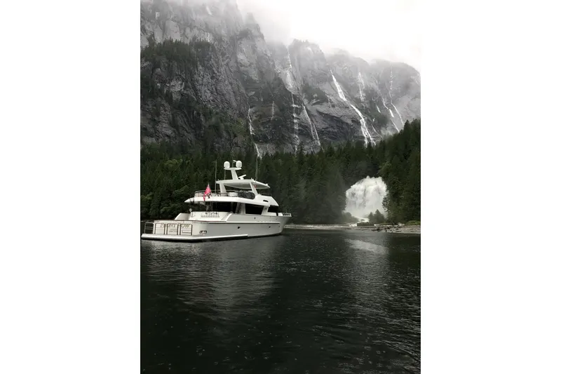 Slide: The Image of 2006 NorthCoast PILOTHOUSE yacht on serene water, surrounded by lush forest. - 4