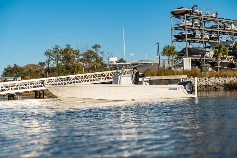 Slide: The Image of 2020 Contender 32 ST boat docked near marina with stacked boats in background. - 6