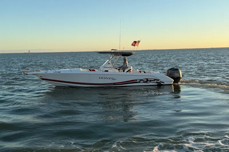Slide: The Image of 1999 Donzi 35 ZF Cuddy boat cruising on open water at sunset. - 10