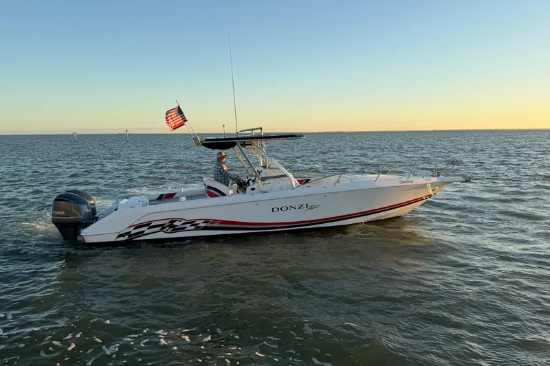 Slide: The Image of 1999 Donzi 35 ZF Cuddy boat cruising on open water at sunset. - 5