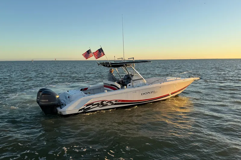 Slide: The Image of 1999 Donzi 35 ZF Cuddy boat cruising on open water at sunset. - 6