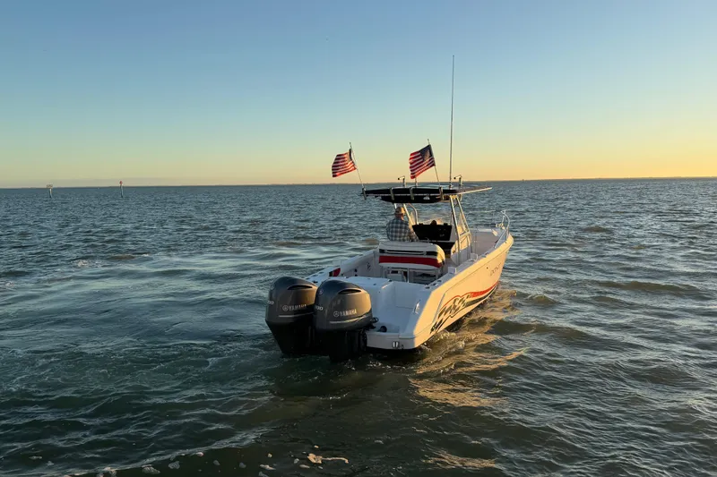 Slide: The Image of 1999 Donzi 35 ZF Cuddy boat cruising on open water at sunset. - 8