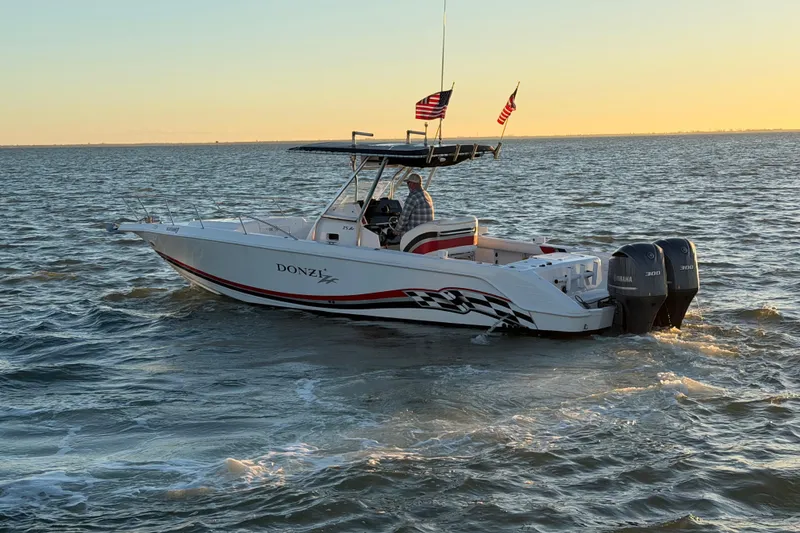 Slide: The Image of 1999 Donzi 35 ZF Cuddy boat cruising on open water at sunset. - 9