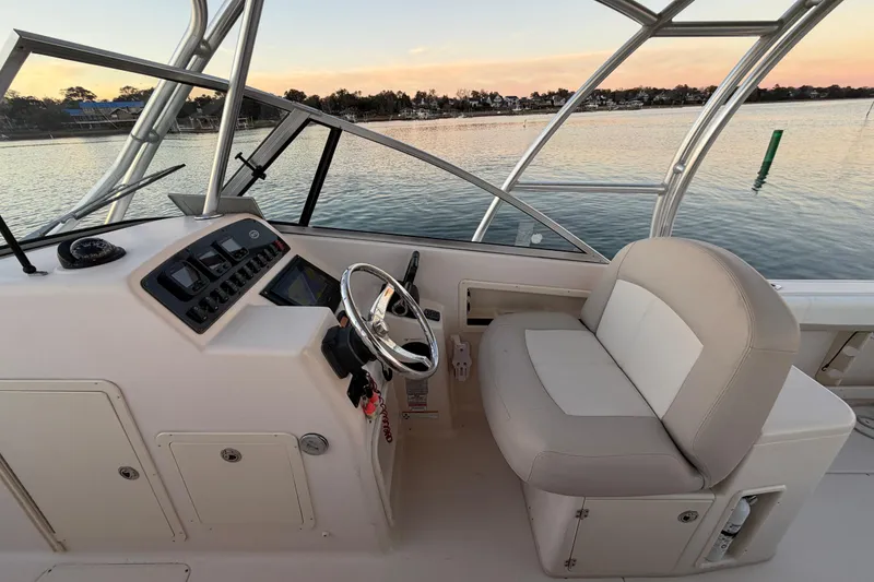 Slide: The Image of 2012 Grady-White Freedom 275 boat interior with steering wheel and seating, on calm water. - 37