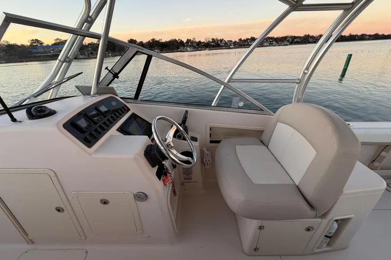 Slide: The Image of 2012 Grady-White Freedom 275 boat interior with steering wheel and seating, overlooking calm waters. - 38