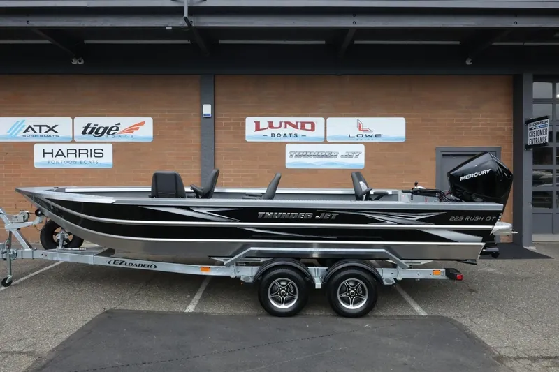 The Image of 2026 Thunder Jet 229 Rush OT boat on trailer, displayed outside dealership. - 1